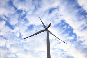 the propeller of wind turbine against the blue sky and cloudy in background photo