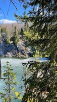 stone quarry lake covered with thin ice. nature of Europe with rocks, green pine forest and pond. vertical photography of landscape taken on sunny day photo