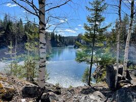 Summer Karelia landscape with birch trees and lake in quarry. photo of Lake in deep marble canyon on sunny day. tourism in Ruskeala Mountain Park in Republic of Karelia. northern nature of Russia