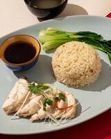 Hainanese chicken rice is a dish consisting of delicious steamed white chicken cut into pieces and served over fragrant rice photo