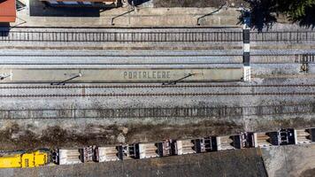 Aerial view of Portalegre railway station, featuring the word Portalegre spelled out in stone on the platform, with cargo wagons visible on the tracks. photo