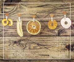 Dry slice fruits apple, banana, orange, pineapple, pear on a wooden background with frame photo