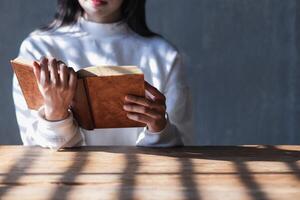 The young woman held a Bible in her hand and tried to learn and understand God teachings from the Bible she held. Concepts of belief and the power of faith in God and teachings from the Bible. photo