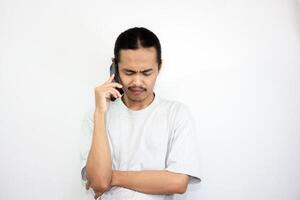 Asian man with sad expression while receiving incoming call from his cell phone. isolated in white background photo