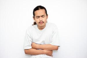 young asian man touching his stomach with pain expression isolated on white background. photo