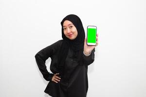 Portrait of young Muslim woman in black shirt and pointing towards the phone. isolated on a white background photo