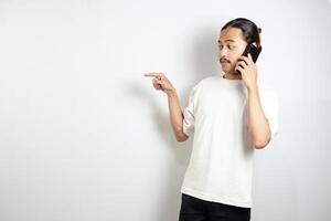 Asian man holding cell phone. pointed to the side and pointed at his cellphone. isolated in white background photo