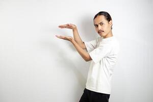 Asian man in white t-shirt pointing to the side. isolated on white studio background. photo