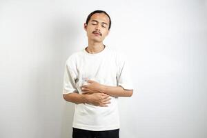 Young Asian man. suffering from severe stomach ache. isolated on white. photo