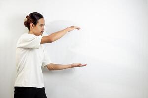 Asian man in white t-shirt pointing to the side. isolated on white studio background. photo