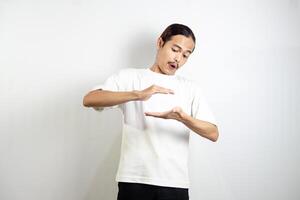 Asian man in white t-shirt pointing down. isolated on white studio background. photo