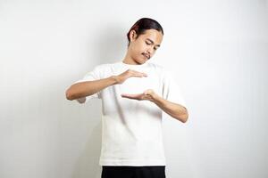Asian man in white t-shirt pointing down. isolated on white studio background. photo