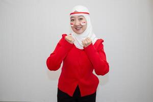 Woman in white hijab wearing red shirt. celebrating Indonesia's independence day. with clenched fists and excitement. isolation on white background. photo
