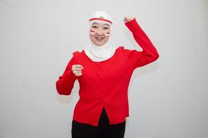 Woman in white hijab wearing red shirt. celebrating Indonesia's independence day. with clenched fists and excitement. isolation on white background. photo