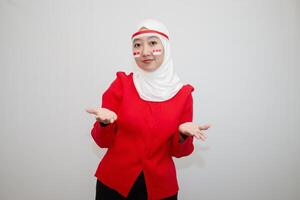 Woman in white hijab wearing red sweater. celebrating Indonesia's independence day. with an expression of offering. isolation on white background. photo