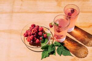Ripe red raspberry drink in a transparent glass wooden background, summer seasonal food and refreshing drinks photo