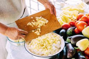 A woman is engaged in the preparation and processing of various fresh farm vegetables photo