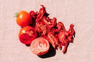 Fresh and dried tomatoes lie on the kitchen table, top view. Harvesting and processing of vegetables, vegetarianism photo
