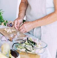A woman is engaged in the preparation and processing of various fresh farm vegetables photo