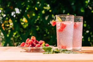 Drink from ripe red raspberries in two transparent glasses, summer background. Summer seasonal freshly refreshing drink photo