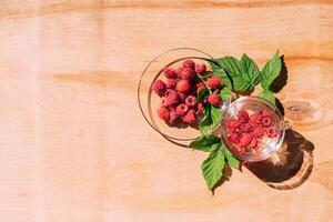 Ripe red raspberry drink in a transparent glass wooden background, summer seasonal food and refreshing drinks photo