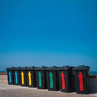 Black plastic garbage cans near the sea. Containers for different rubbish on a background of blue sky. Garbage sorting for further processing. photo