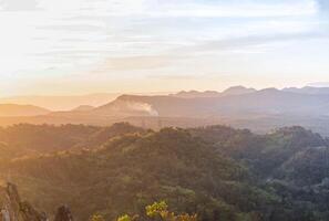 The stunning view from a tourist's standpoint as they go down a hill on a foggy trail with a hill and a background of a golden sky in Forest Park, Thailand. Rainforest. Bird's eye view. Aerial view. photo