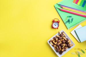 School supplies and cookies for a snack on the yellow table with copy space. concept school photo