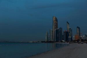 Public beach with high-rises and buildings of the city of Abu Dhabi, UAE late evening after sunset photo