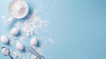 top view background for baking, flour, eggs, whisk, cake spatula. blue background photo