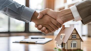 successful real estate transaction, realtor and buyer shaking hands, model of house and folder with documents on table photo