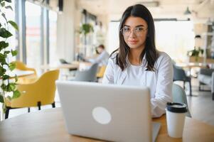 Smiling girl student study online with skype teacher, happy young woman learn language listen lecture watch webinar write notes look at laptop sit in cafe, distant education photo