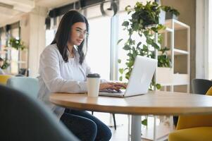 Smiling girl student study online with skype teacher, happy young woman learn language listen lecture watch webinar write notes look at laptop sit in cafe, distant education photo