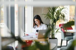 Smiling girl student study online with skype teacher, happy young woman learn language listen lecture watch webinar write notes look at laptop sit in cafe, distant education photo