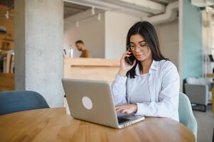 Smiling girl student study online with skype teacher, happy young woman learn language listen lecture watch webinar write notes look at laptop sit in cafe, distant education photo