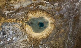 Aerial view of a geothermal hot spring in Strokkur Iceland, showcasing the unique geological formations and vibrant blue water. photo