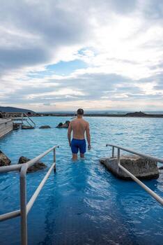 Man relaxing in the blue waters of a geothermal lagoon in Iceland photo