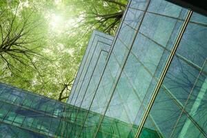 Eco-friendly building in modern city. Sustainable glass office building with trees for reducing carbon dioxide. Office building with green environment. Corporate building reduce CO2. Net zero emission photo