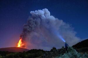 A lone figure stands on a hill, flashlight in hand, searching for answers in the darkness photo