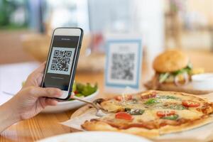 Woman use smartphone to scan QR code to pay in cafe restaurant with a digital payment without cash. Choose menu and order accumulate discount. E wallet, technology, pay online, credit card, bank app. photo