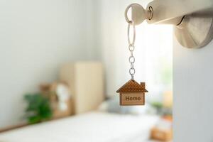 Moving house, relocation. The key was inserted into the door of the new house, inside the room was a cardboard box containing personal belongings and furniture. move in the apartment or condominium photo