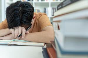 Asian student man have anxiety because of exams, male prepare for test and learning lessons in the library. stress, despair, haste, misunderstanding reading, discouraged, expectation, knowledge, tired photo