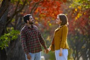 Happy caucasian couple walking together in public park during autumn with maple and beech tree for fall color travel destination and family happiness photo