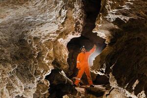 Man walking and exploring dark cave with light headlamp underground. Mysterious deep dark, explorer discovering mystery moody tunnel looking on rock wall inside. photo