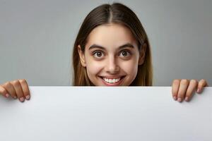 Woman Holding White Blank Copy Space Poster With Smiling Expression On Grey Background For Advertisement, Marketing, And Communication Design Concepts, Suitable For Holiday Greeting Cards photo