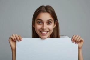 Enthusiastic Woman Holding Blank White Copy Space Paper with Joyful Facial Expression on Grey Background for Advertisement or Message Promotion photo