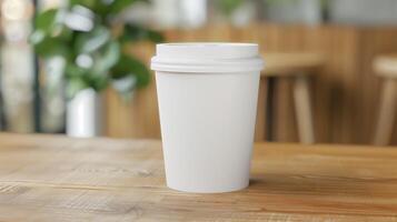 Sleek Minimalist White Disposable Coffee Cup on Wooden Table in Cozy Cafe Setting with Blurry Greenery Background photo