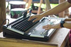 Close up hands are adjusting audio mixer or sound mixer controller machine. Concept, sound controler equipment for Dj or musicians to control level of different sound for entertainment. photo