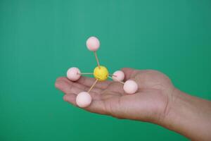Closeup hand hold DIY molecule structure made from toothpicks and plasticine. Concept, teaching aids, educational materials. science lesson about molecule. Creative task from learning. photo
