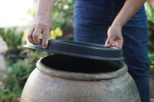 Closeup hands hold lid to cover water jar to protect from mosquitoes to breed inside or other insects or dust go into water. Concept, campaign to stop mosquitoes cycle to lay eggs in water container photo